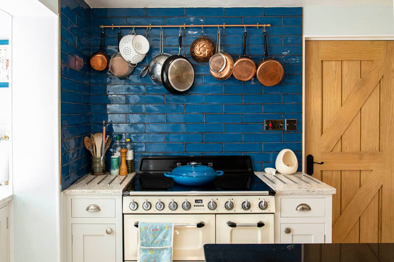 The vibrant blue tiles behind the Smeg Victorian range cooker add a pop of colour that contrasts with the copper pots and pans